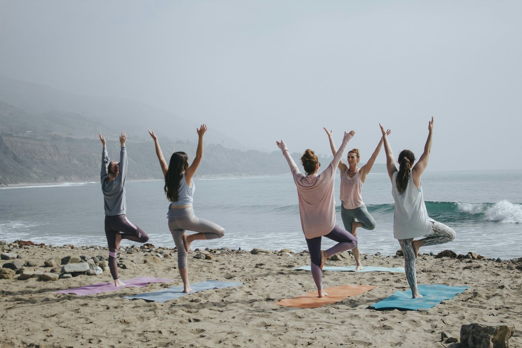 Un groupe en posture de l’arbre sur une plage, face à l’océan